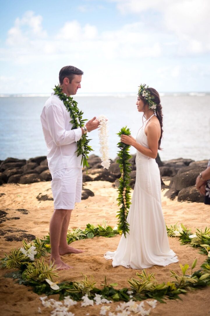 A man and woman standing on the beach holding hands.