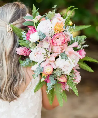 A woman holding a bouquet of flowers in her hand.