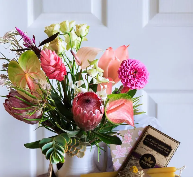 A vase of flowers and some food on the table.