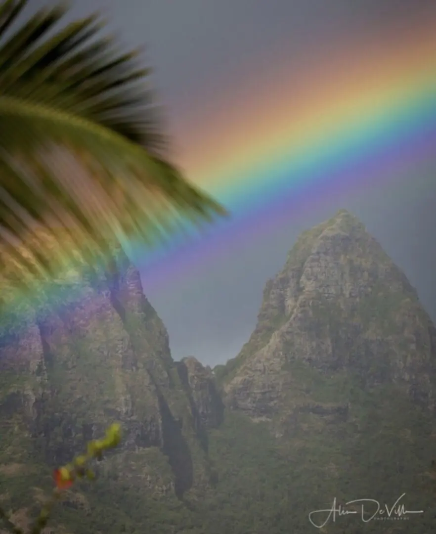 A rainbow is seen in the sky over mountains.