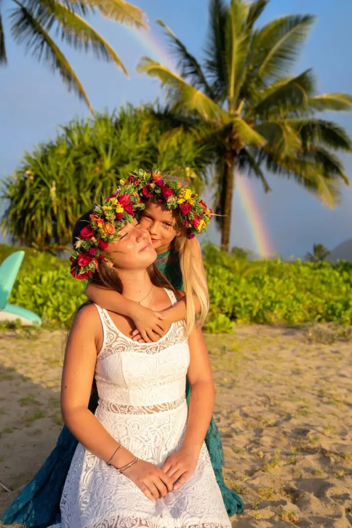 A woman with flowers in her hair and a girl on the beach