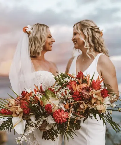 Two women standing next to each other holding a bouquet of flowers.