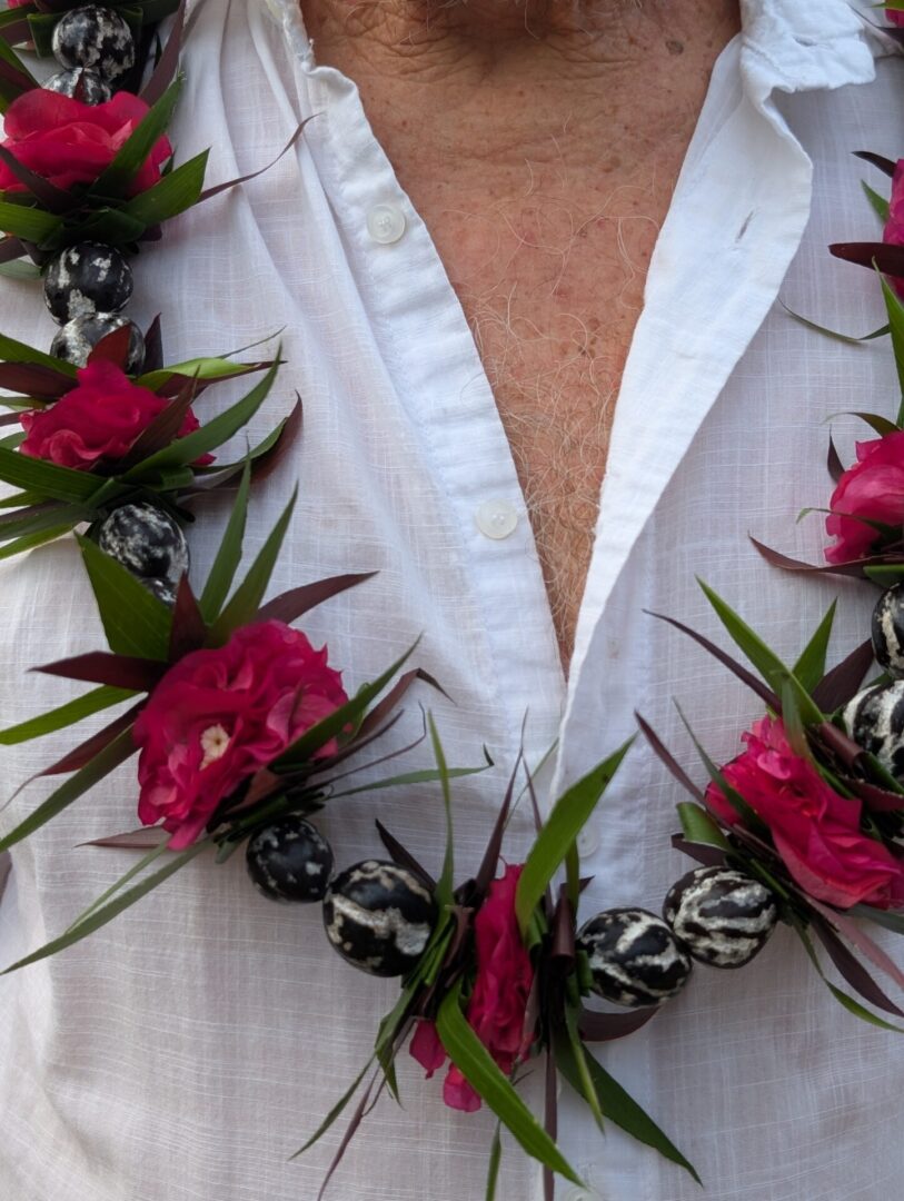 Man in white shirt wearing a red and green lei